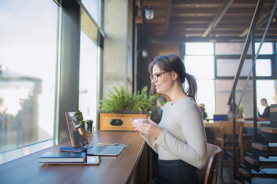 Remote work - happy lady smiling in front of computer drinking tea