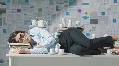 Overworked female office professional sleeping in office in the background, with the text 'how to prevent employee burnout in 2022'