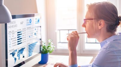 Businesswoman using business analytics or intelligence dashboard on computer screen