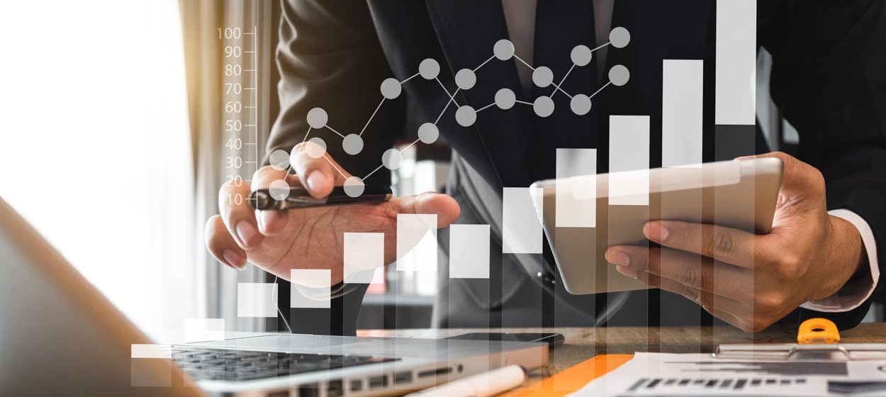 Businessman in front of laptop making calculations with spreadsheets, tablet and BI tools