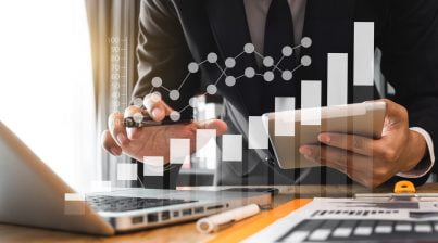 Businessman in front of laptop making calculations with spreadsheets, tablet and BI tools