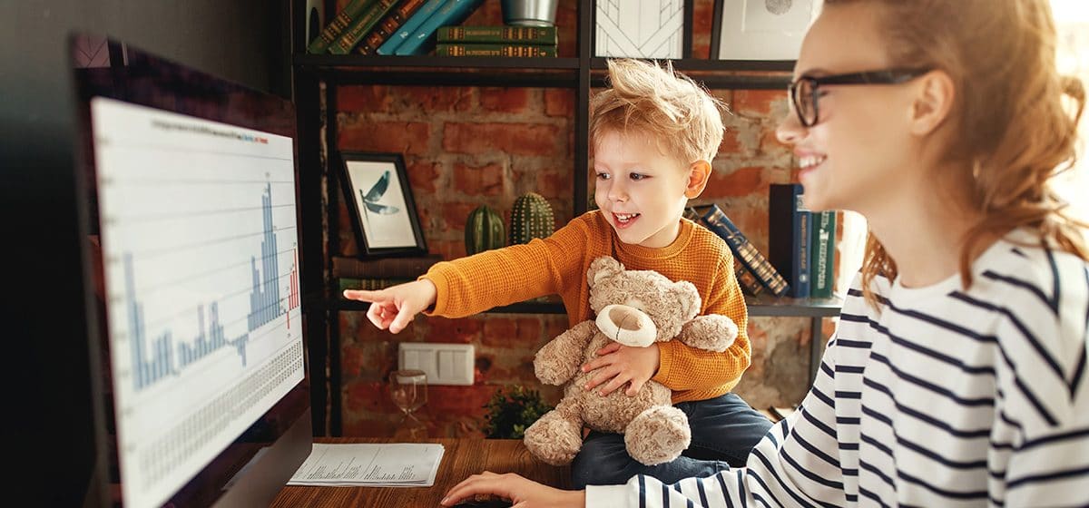 Remote worker conducts data analysis with her child pointing at the screen