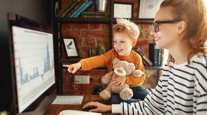 Remote worker conducts data analysis with her child pointing at the screen