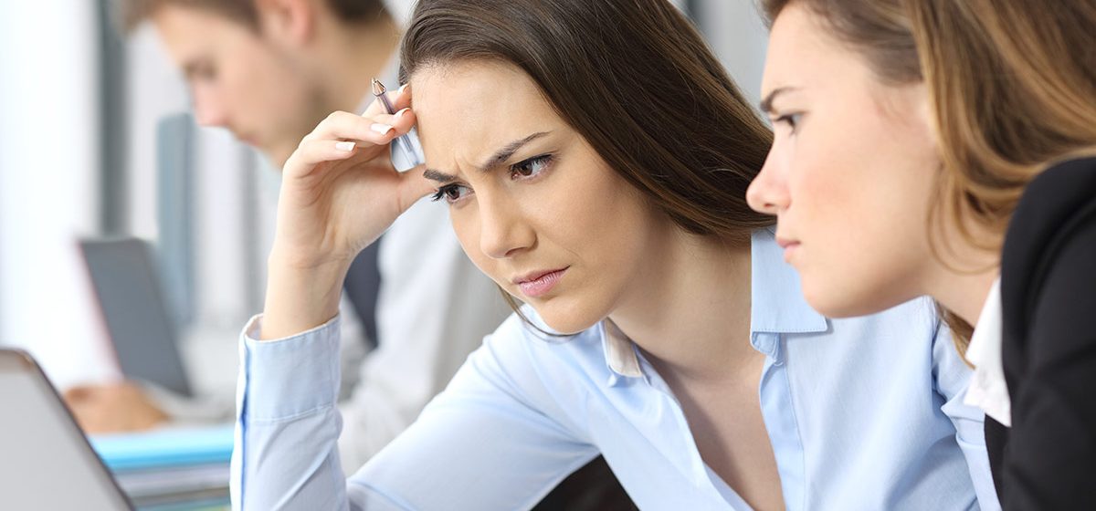 Worried businesswomen working to solve complicated HR data and analytics issues in front of laptop