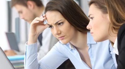 Worried businesswomen working to solve complicated HR data and analytics issues in front of laptop