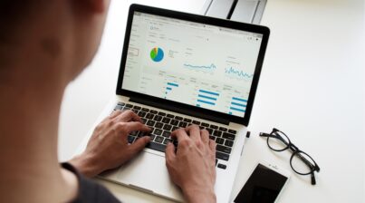 Man working on a laptop that displays graphs and charts