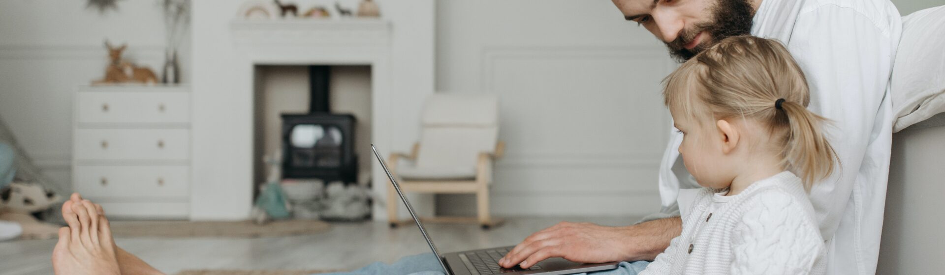 Father working on laptop next to child