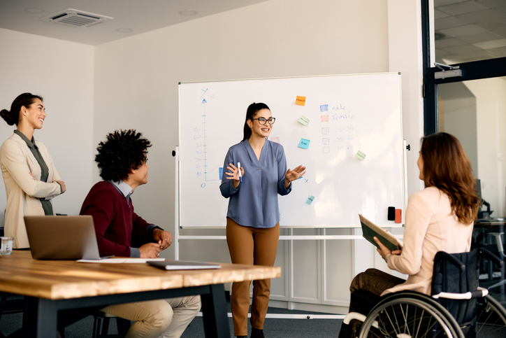 Young presenter talking to a diverse team in the office