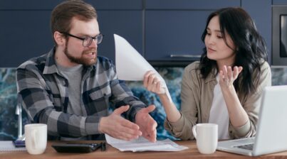 Man and women frustrated and pointing at paperwork